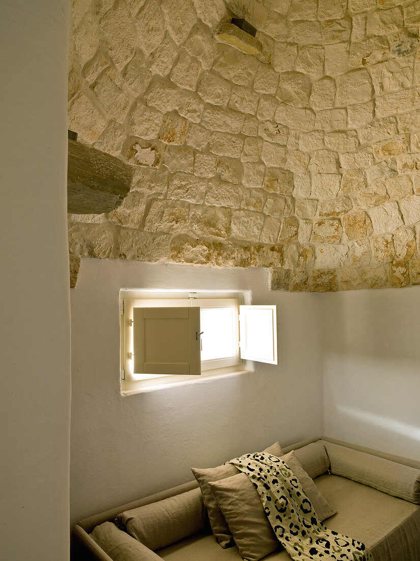 Modernes Sofa unter kleinem Fenster in einem Trullo