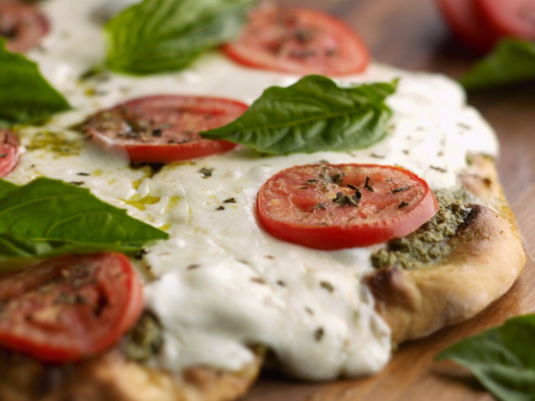 Homemade Pesto Pizza with Mozzarella Cheese, Tomato Slices and Fresh Basil