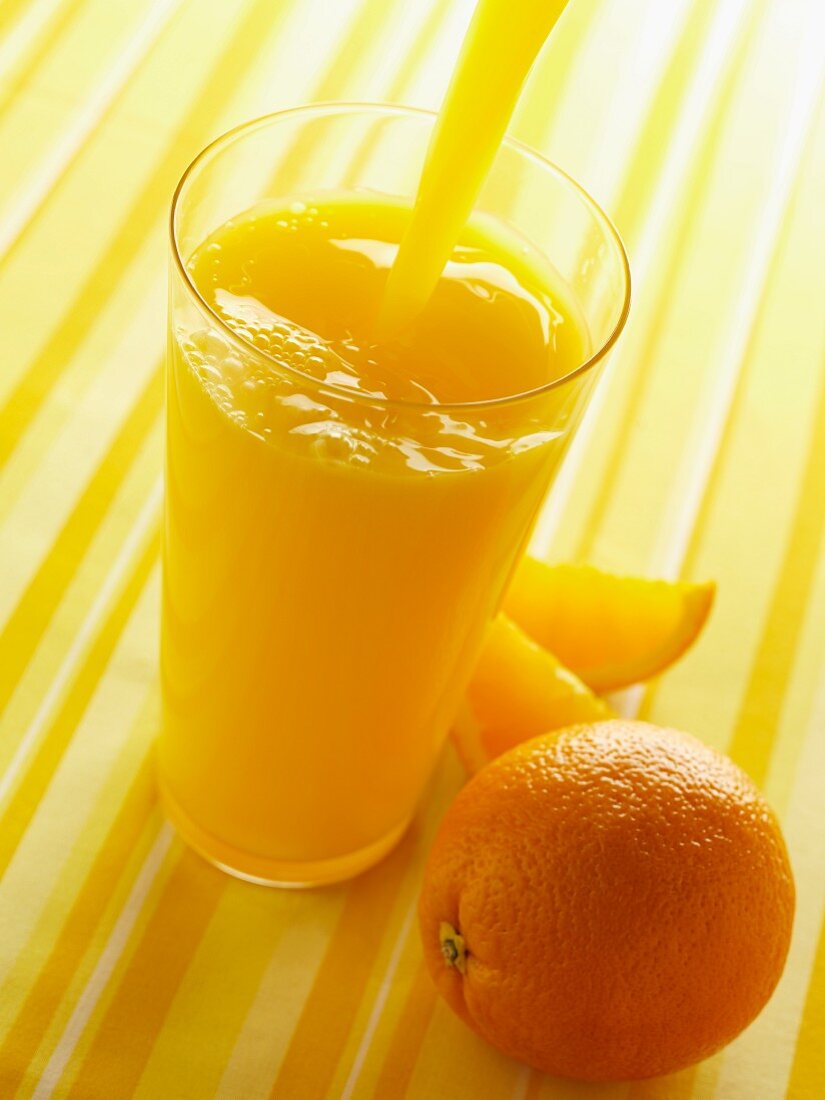 Orangensaft in ein Glas einschenken
