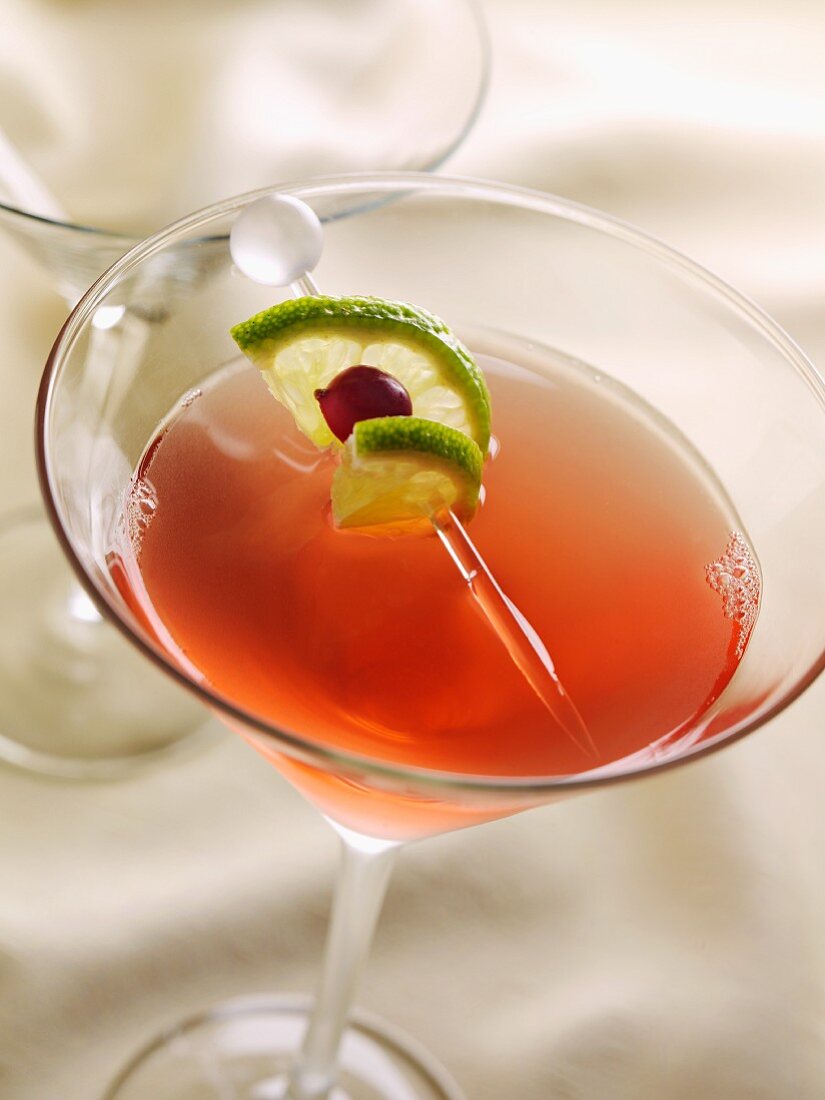 Cosmopolitan with Skewered Lime and Cranberry in a Martini Glass