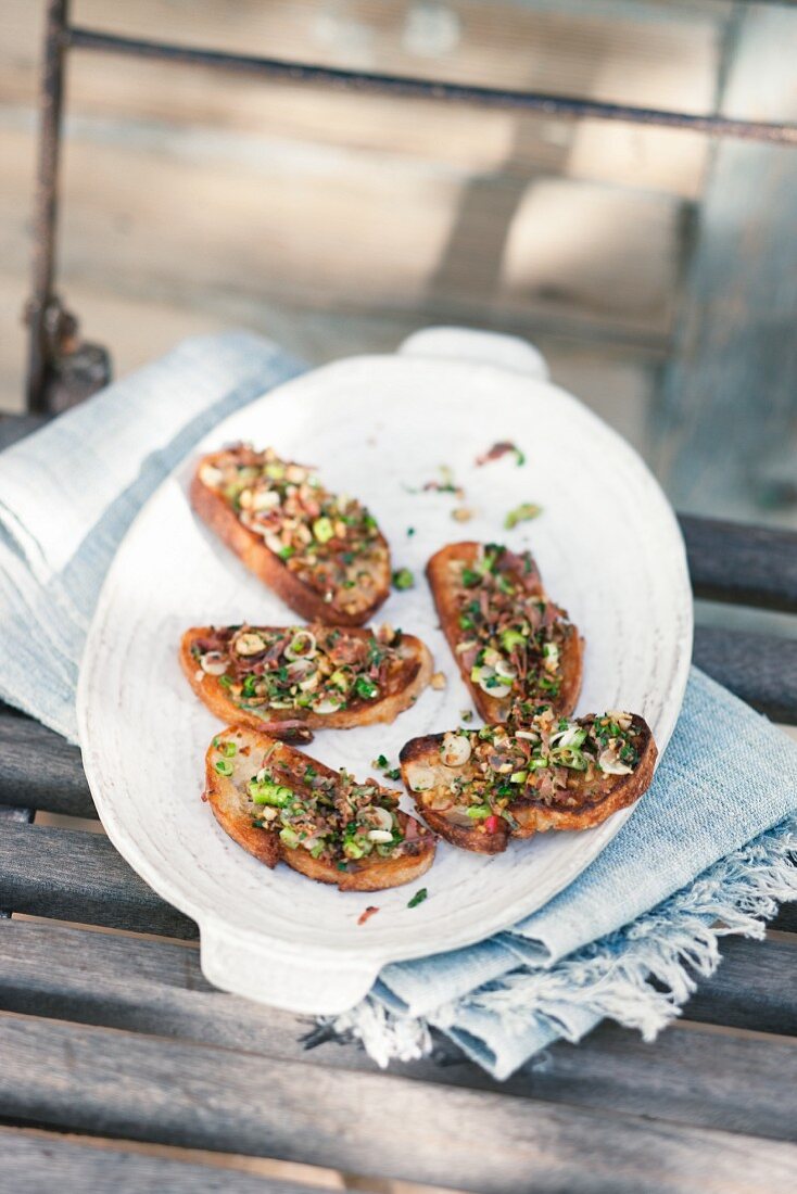 Crostini topped with spring onions, Parma ham and nuts