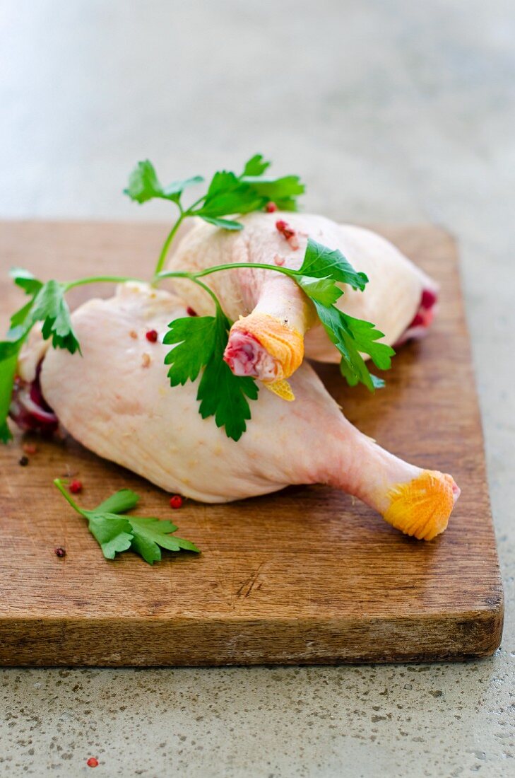 Raw duck legs with parsley on a chopping board