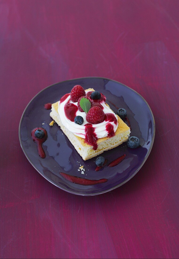 A slice of sponge cake with cream and berries