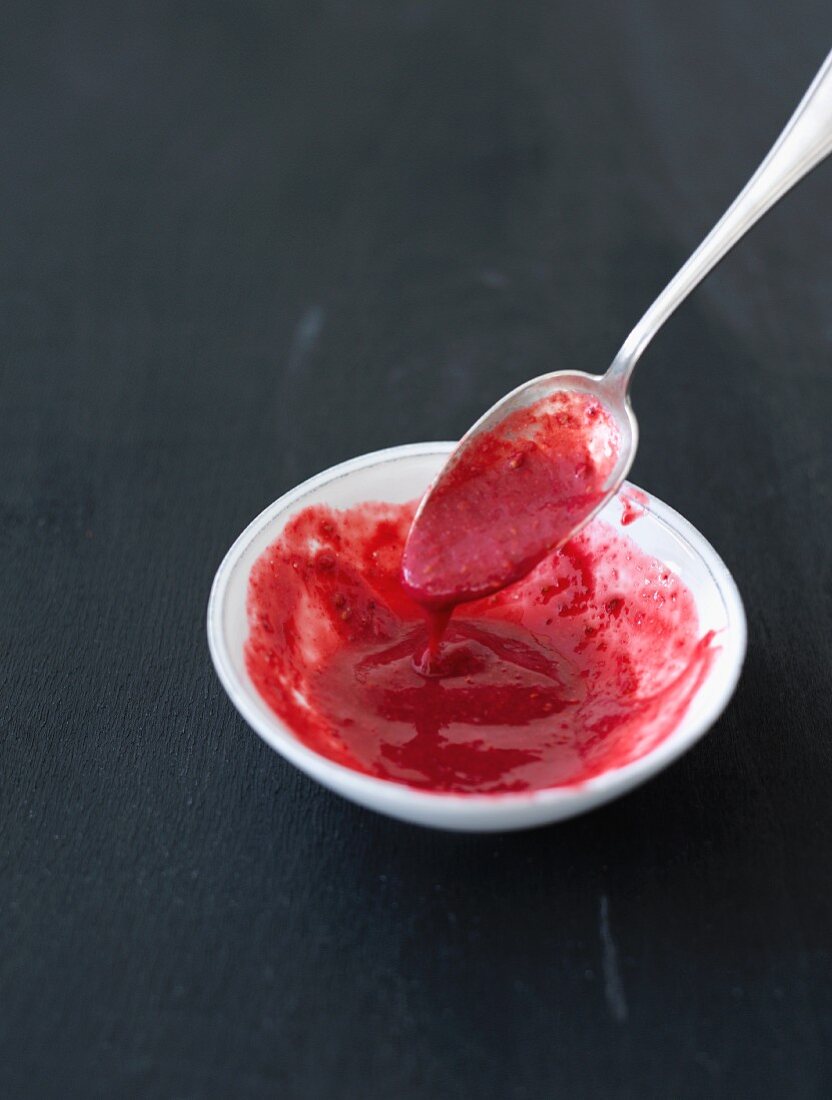 Raspberry sauce in a bowl and on a spoon