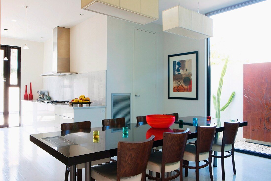 Dark wood dining table and chairs in open-plan interior with view of kitchen