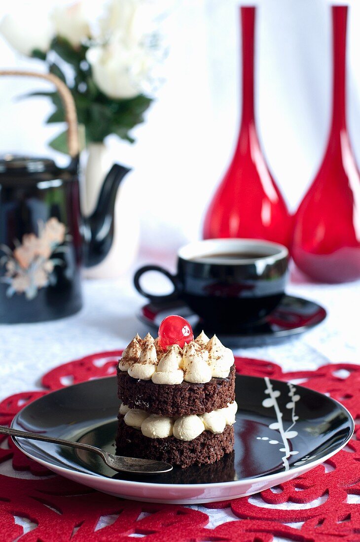 A chocolate cake with vanilla cream and a cocktail cherry