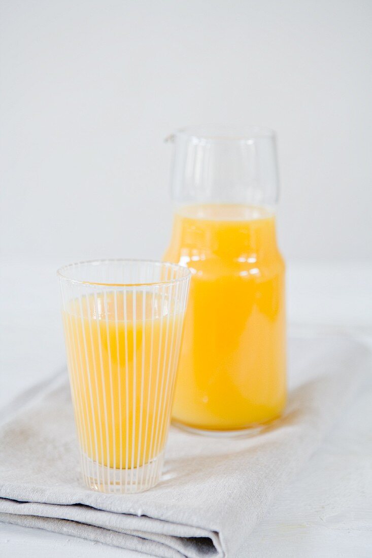 Orangensaft in Glas und Karaffe