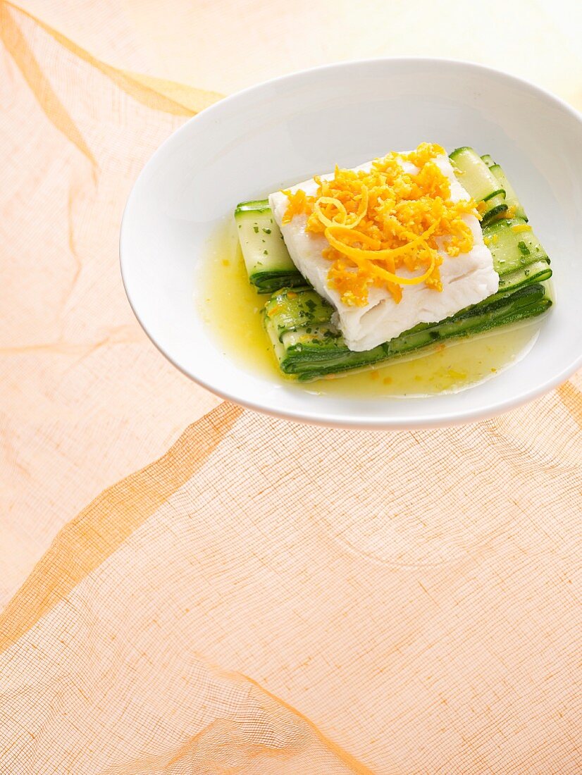 Cod fillet with orange zest on zucchini slices