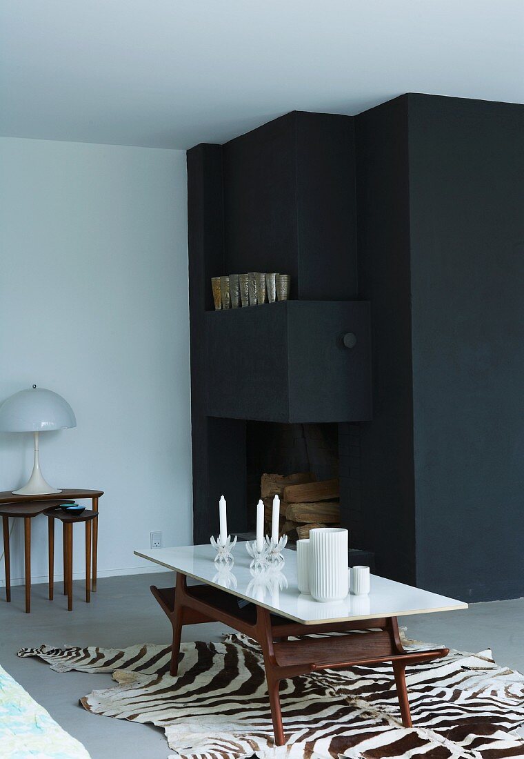 Fifties-style coffee table on zebra-skin rug in front of black painted corner with fitted cupboard