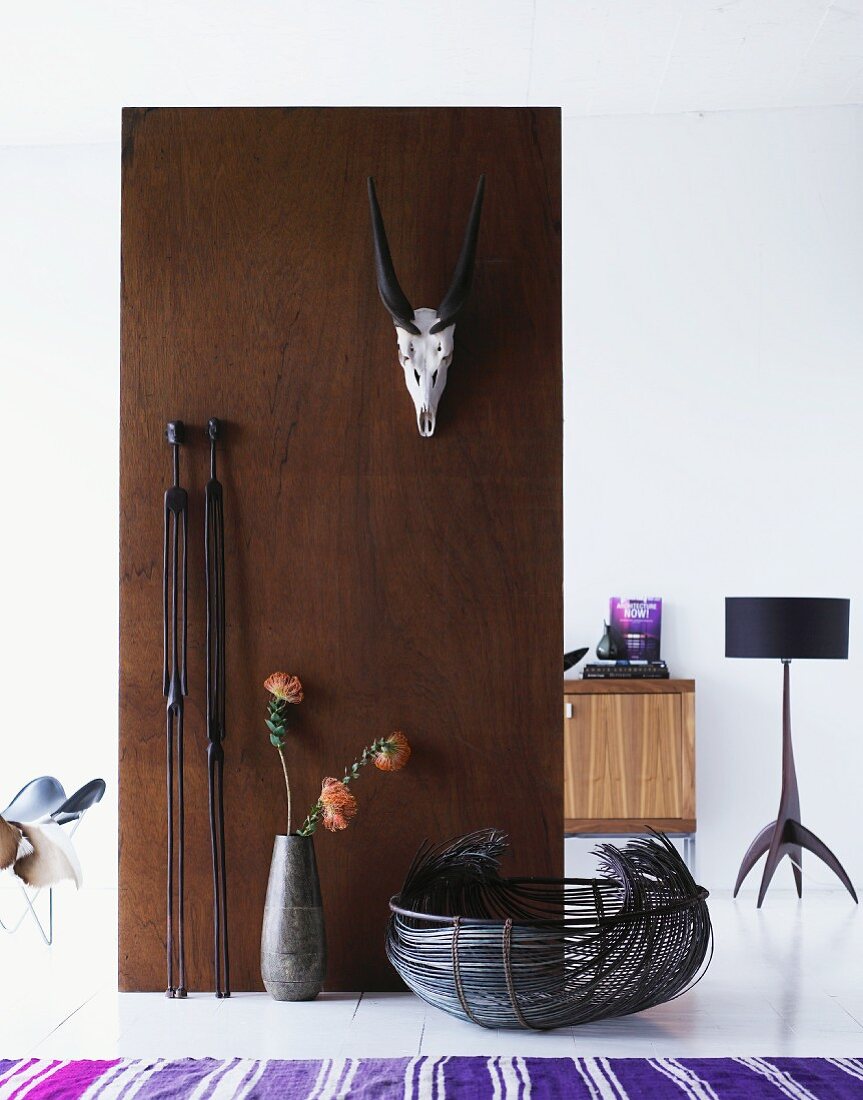 Animal trophy mounted on wooden partition and view of standard lamp in room beyond