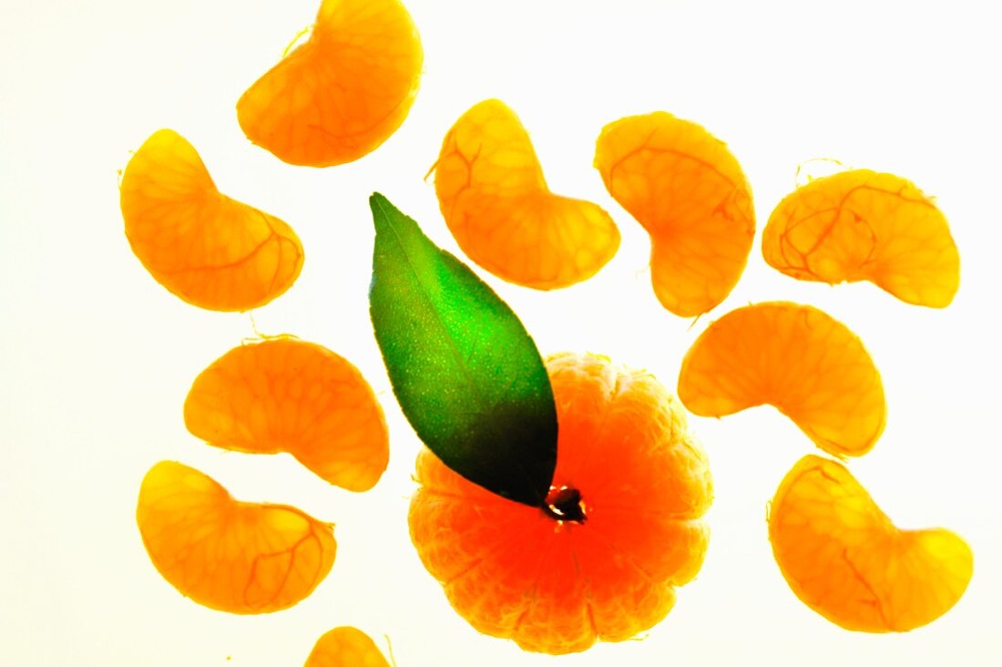 A peeled mandarin with a leaf and wedges