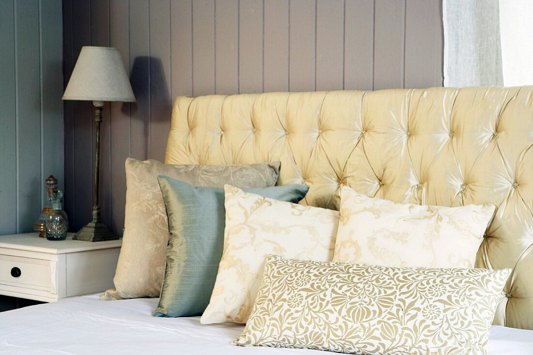 Upholstered headboard and pillows on front of a wooden wall