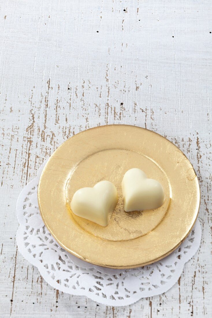 Two white chocolate hearts on a golden plate