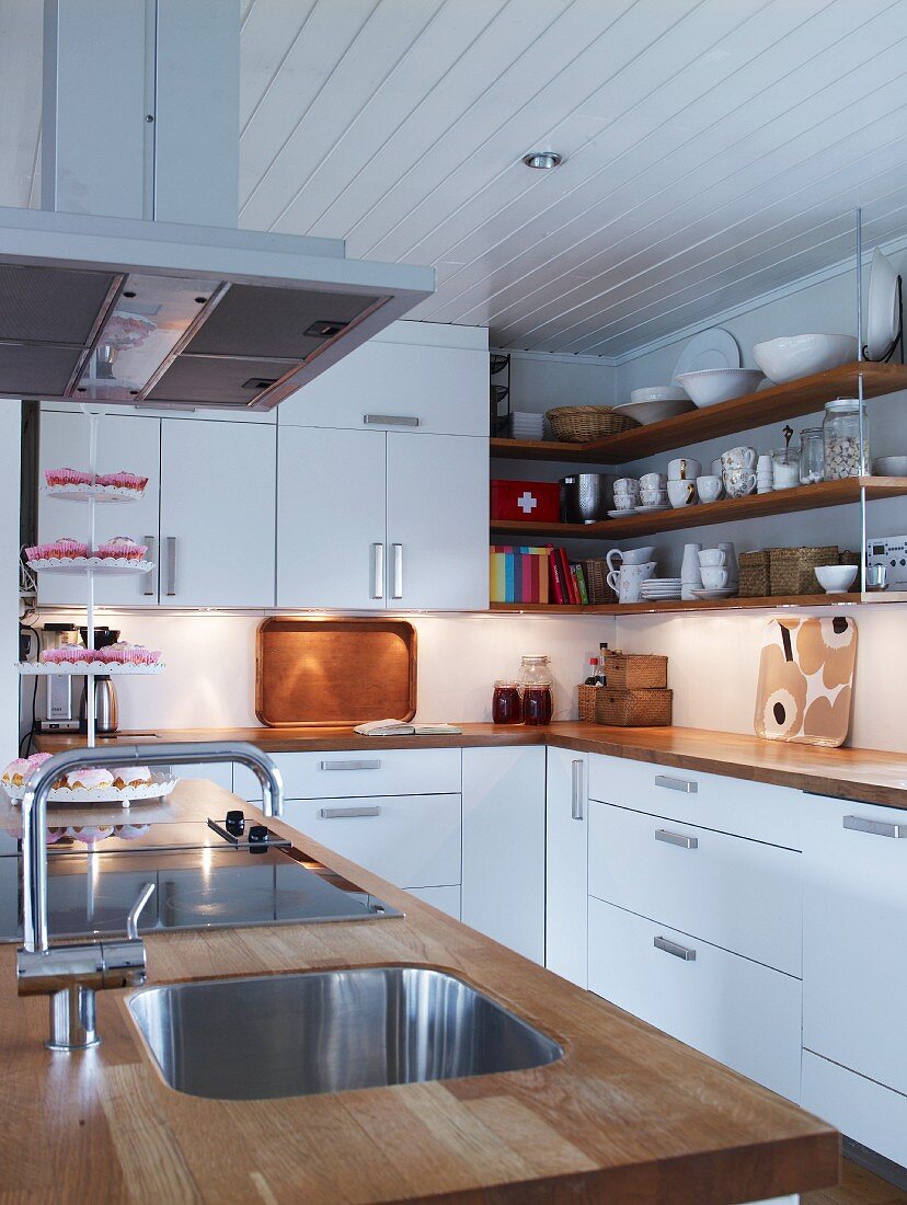 weiße Küche mit Holzarbeitsplatten auf Mittelblock und Unterschränken