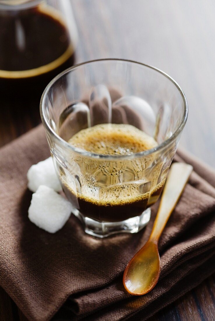 A glass of espresso with sugar cubes