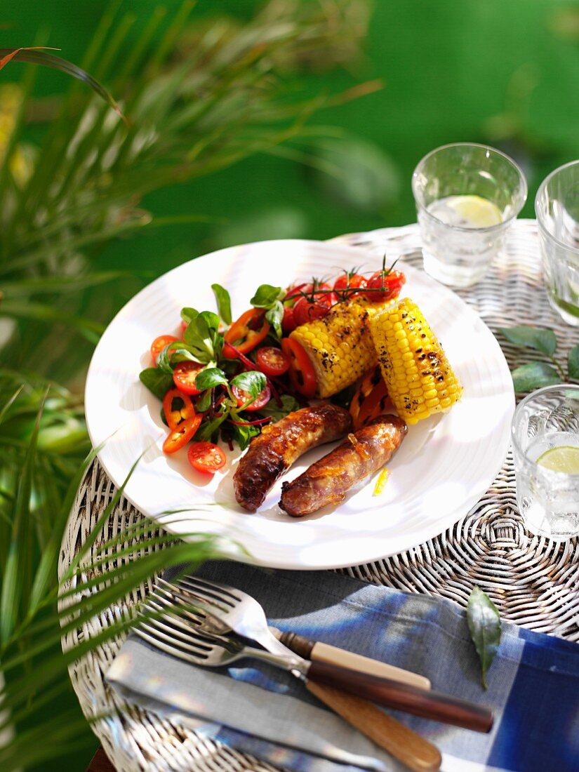 Sausages with orange glaze, corn cobs and a side salad