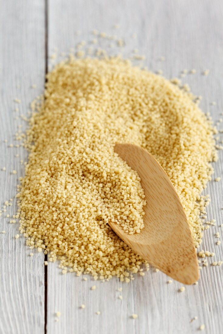 A pile of couscous with a wooden spoon