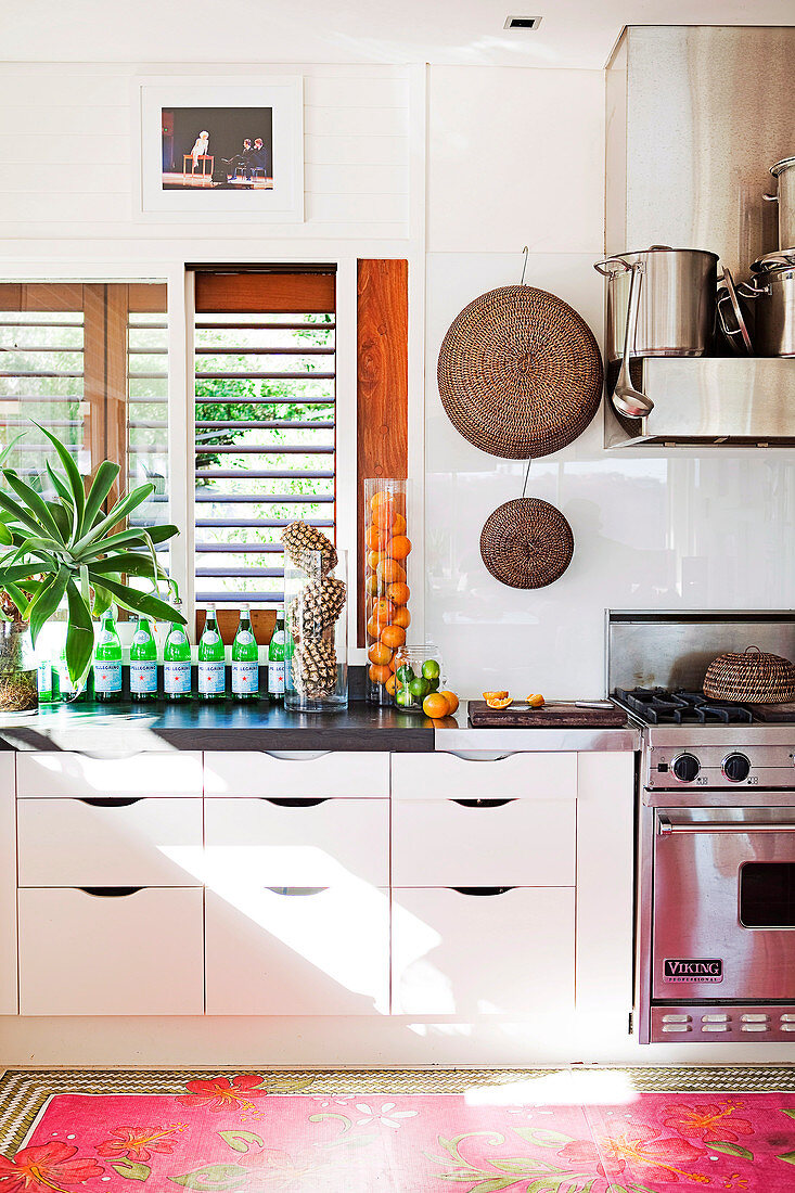 White kitchen with stainless steel appliances, glass splashback and colourful rug