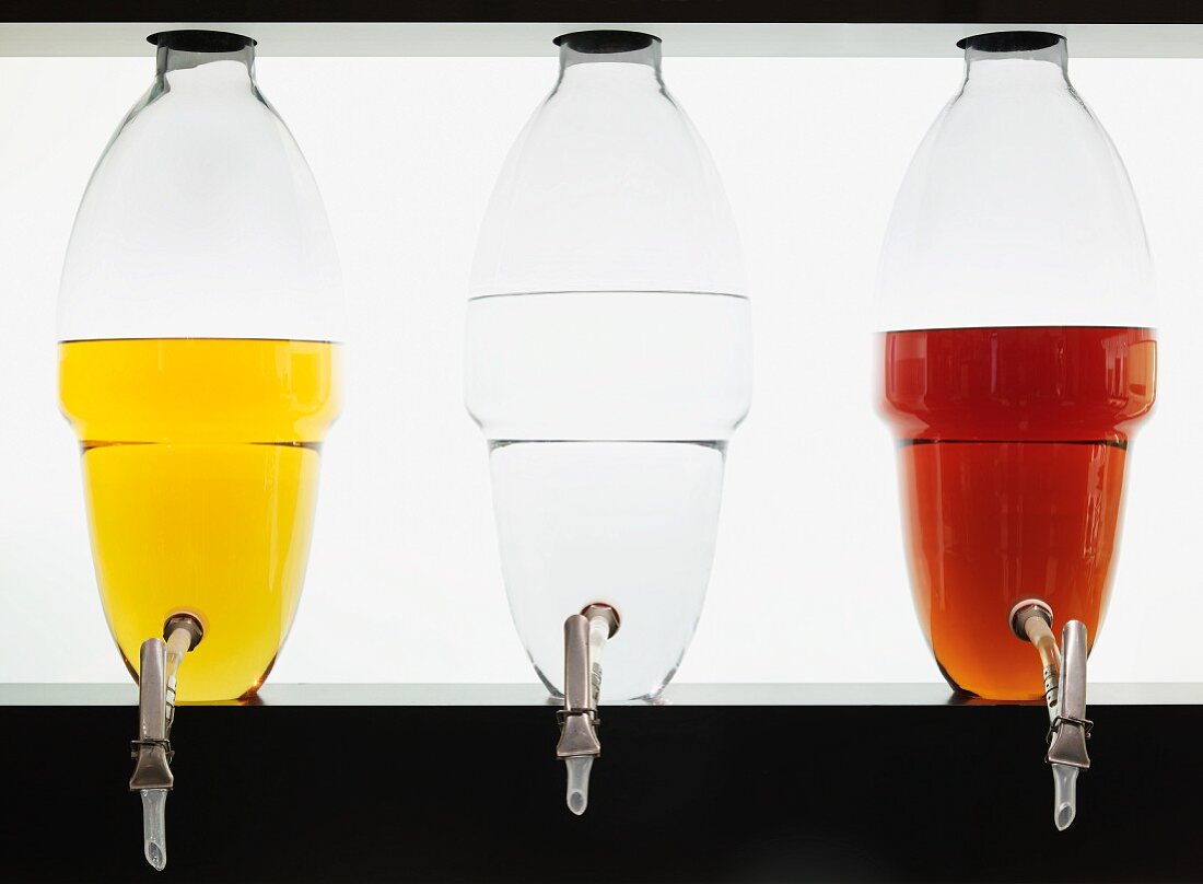Verschiedenfarbige Spirituosen in Glasbottichen: Single Malt, Gin, Weinbrand