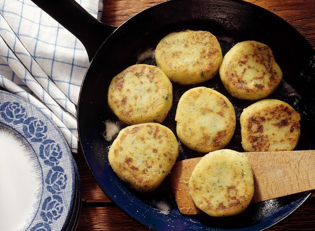 Potato Pancakes in Skillet with wooden Spatula