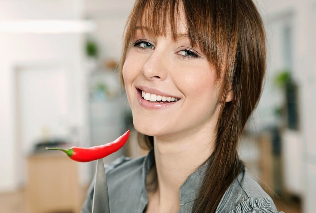 Frau hält Messer mit Chilischote