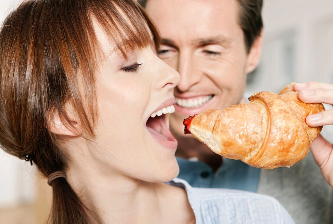 Frau beisst in ein Croissant mit Marmelade