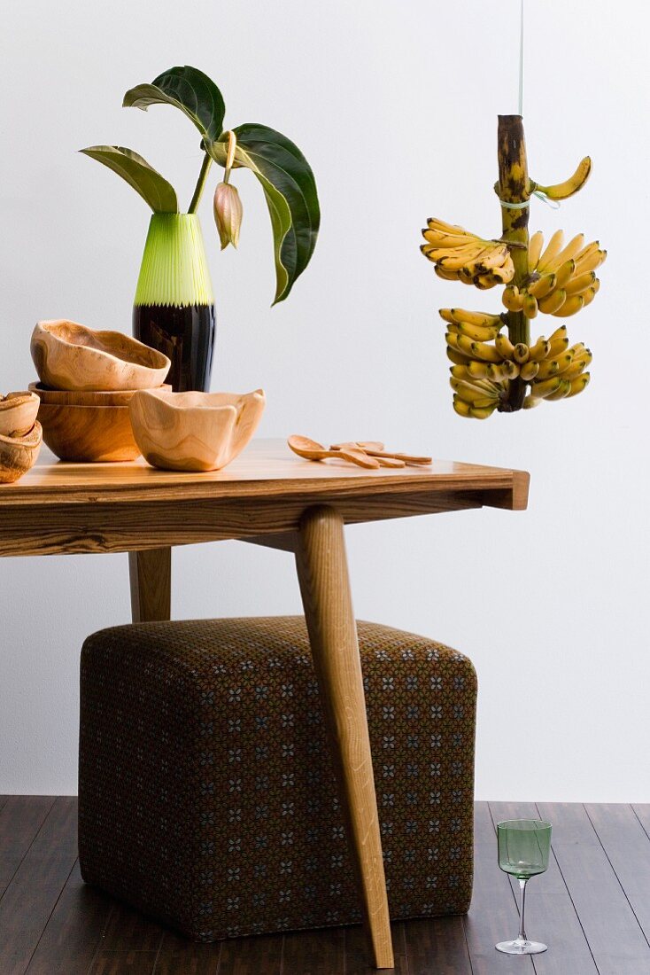 Retro-style living room (wooden table, stool, wooden bowls, banana plant)