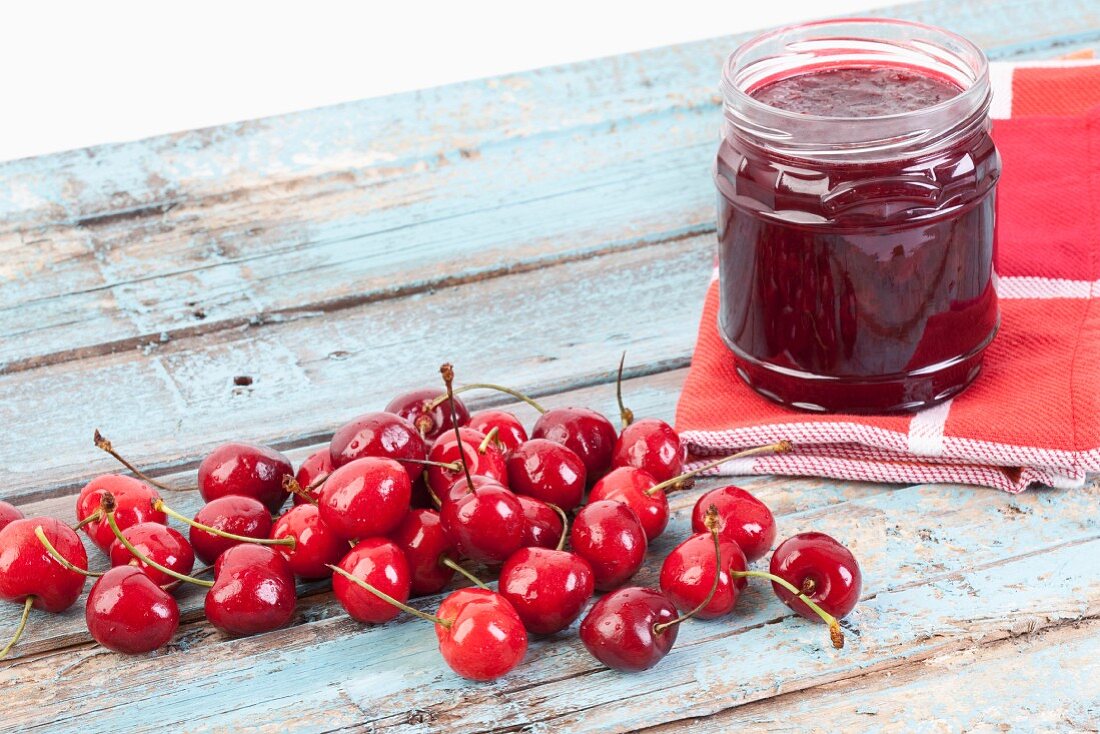 A jar of cherry jam and fresh cherries