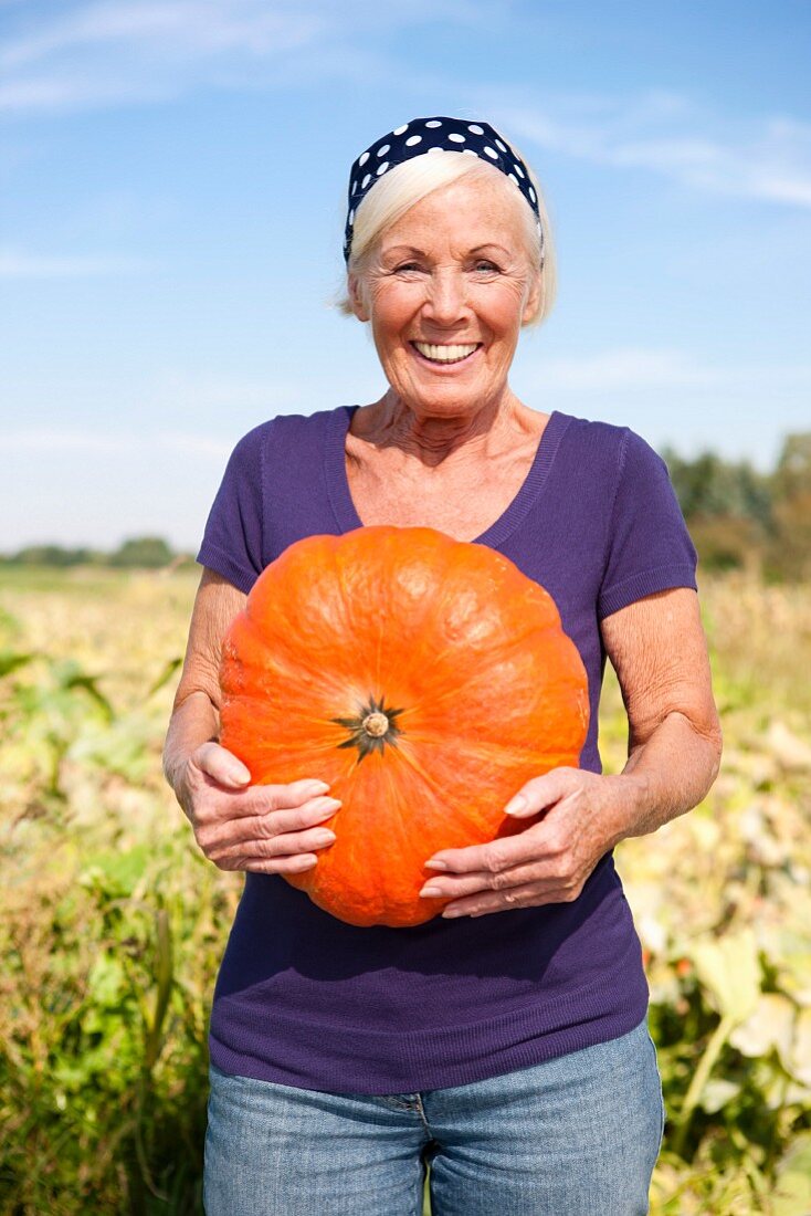 A woman in a field holing a giant pumpkin