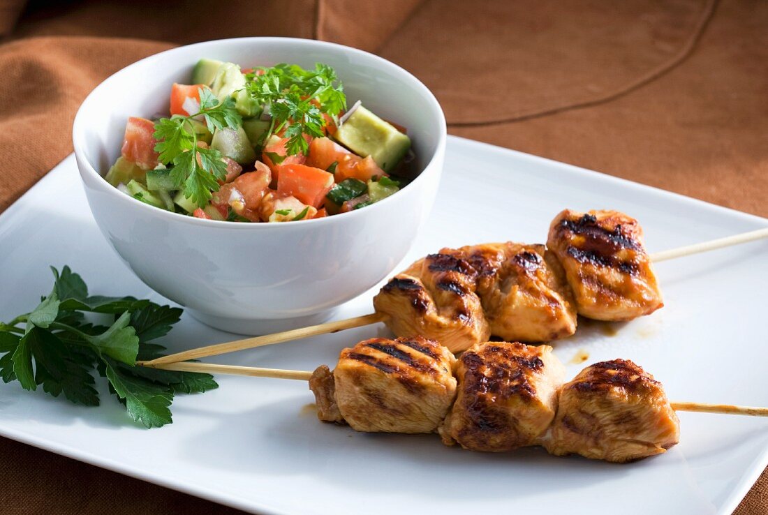 Grilled chicken kebabs with an avocado and tomato salad