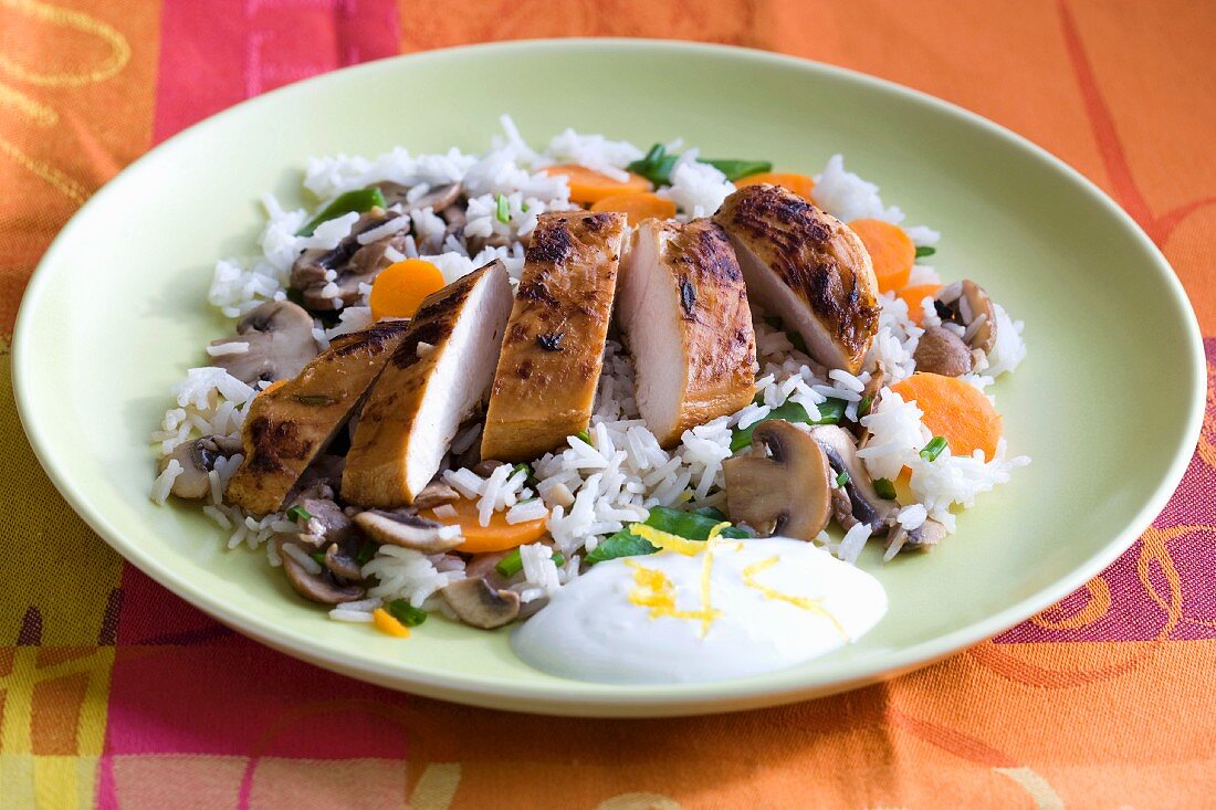 Chicken breast on a bed of rice with carrots, mushrooms and a yogurt dip