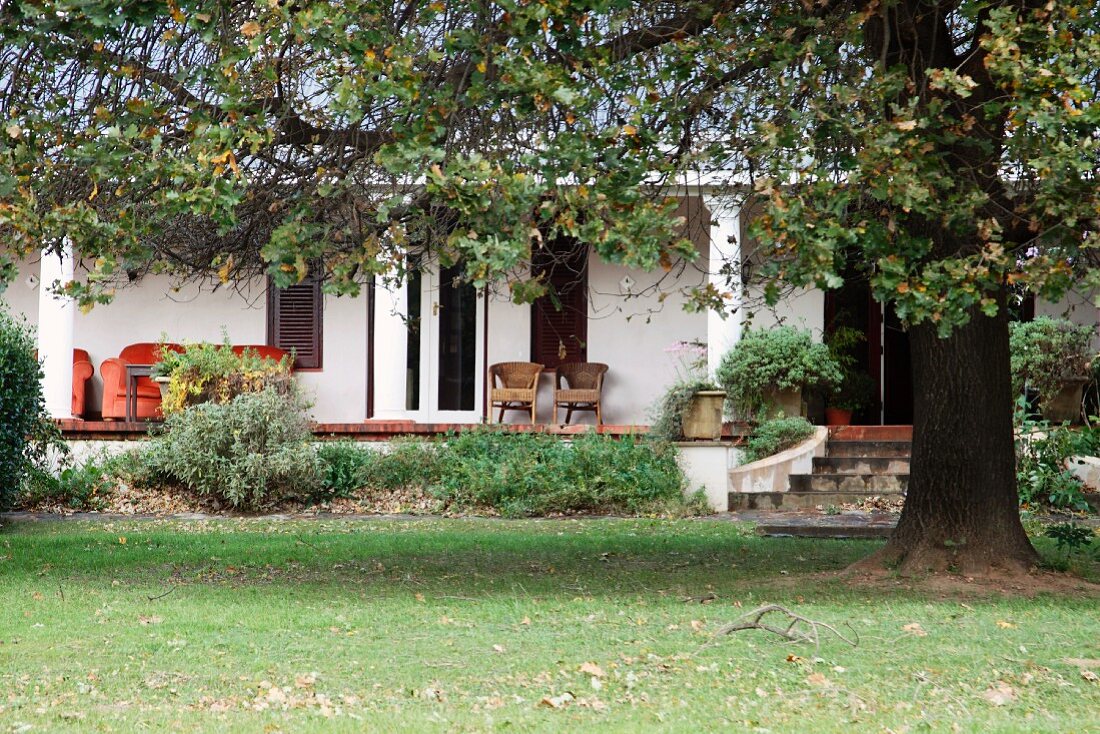 Garten in Herbststimmung vor traditionellem Haus mit Säulen auf Veranda