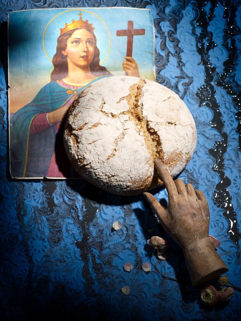 A picture of a saint, a loaf of bread and a wooden hand