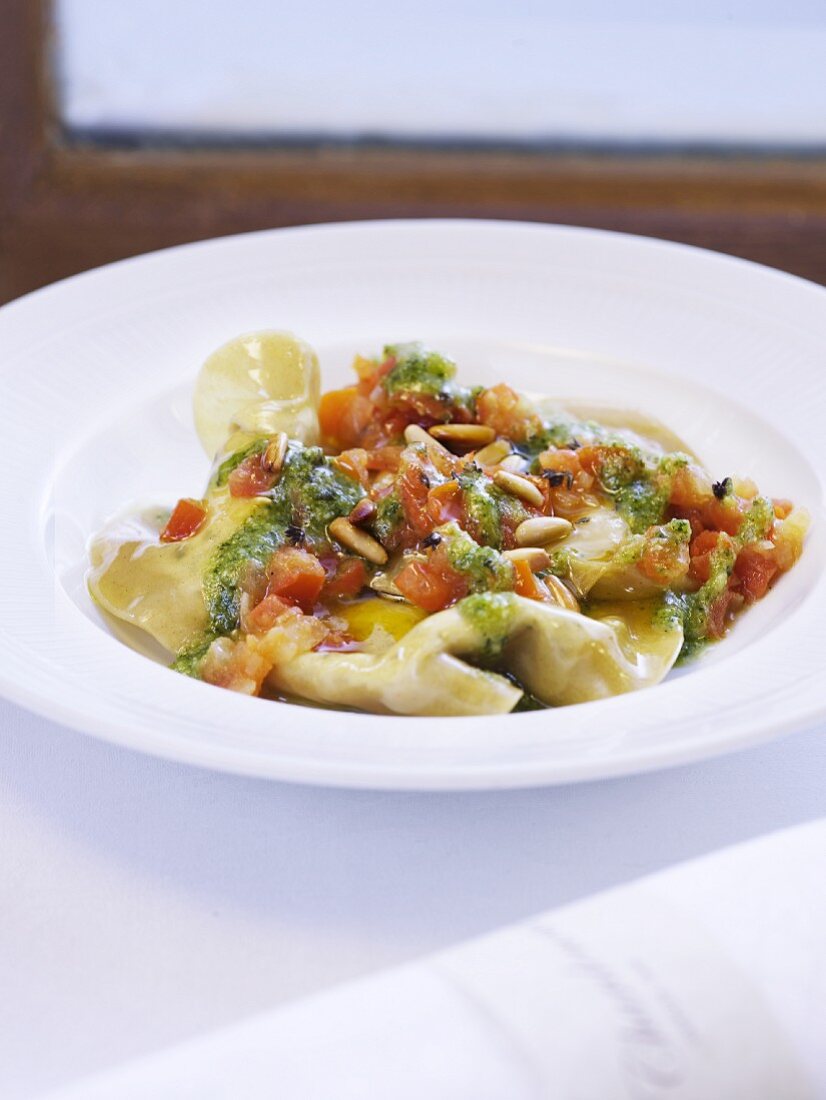 Ravioli filled with Brousse cheese and served with pistou, tomatoes and pine nuts