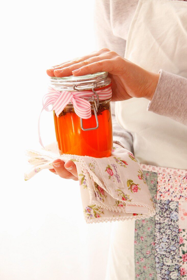 A woman holding a jar of rose jelly