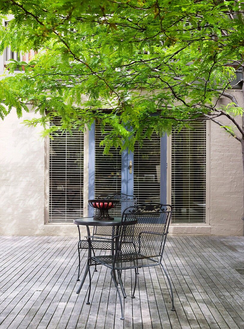 Contemporary terrace with a metal patio table and chair on a wooden floor