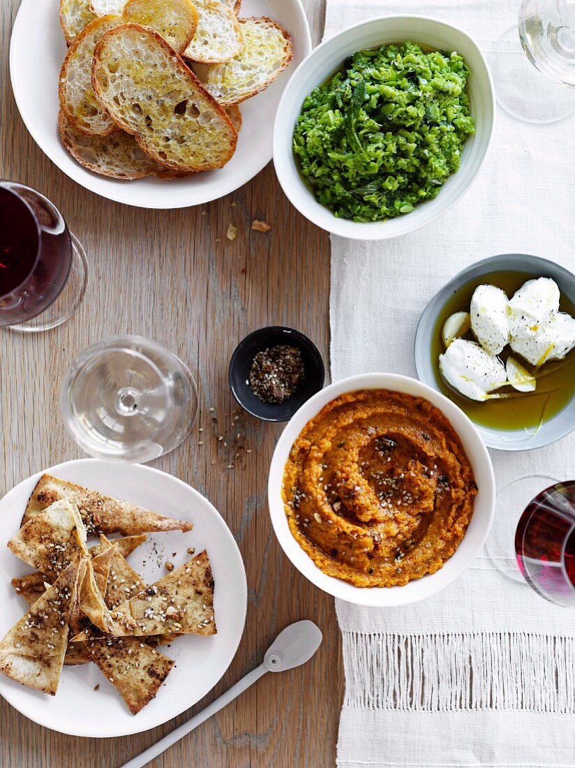 A bean dip and a carrot dip with crostini and pita bread