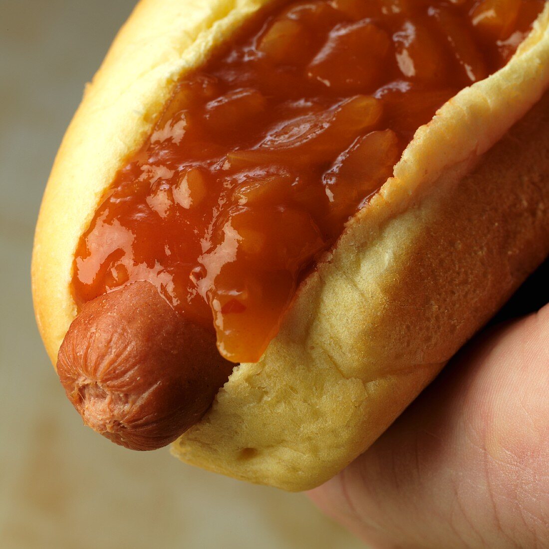 Hand hält Hot Dog mit Zwiebelsalsa