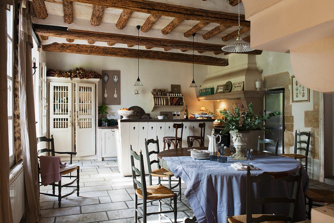 Rustic kitchen-dining room with wooden table; counter with bar stools in background