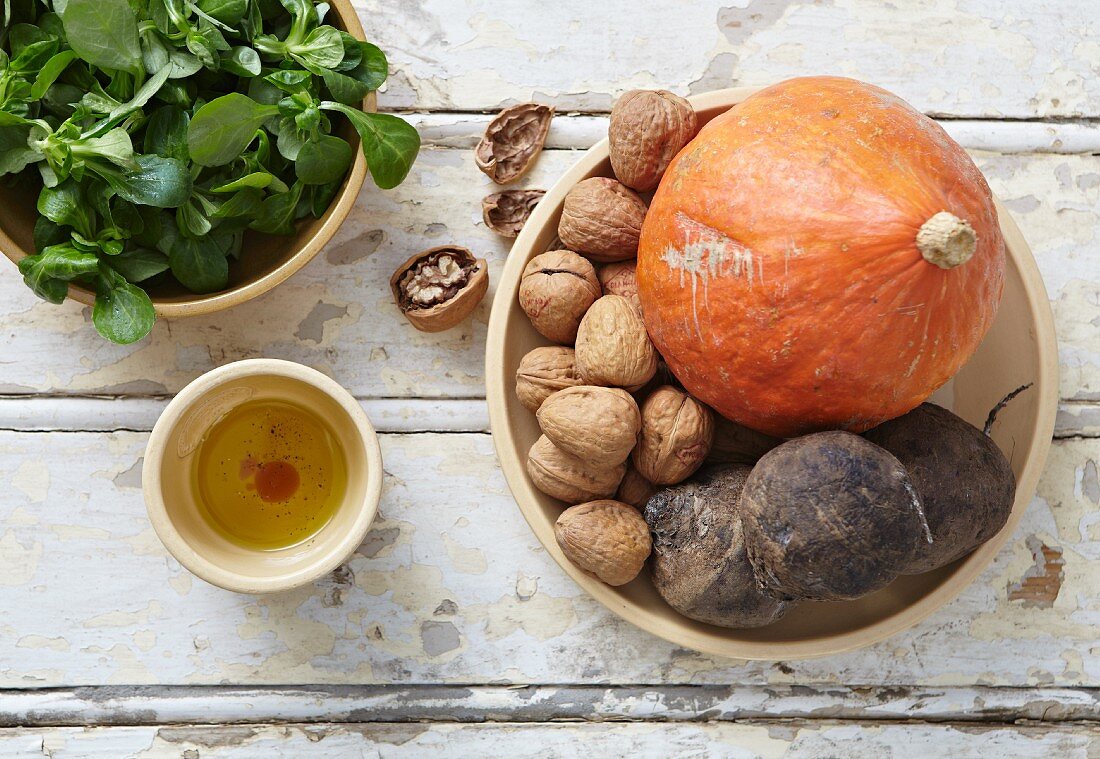 An arrangement of lamb's lettuce, a pumpkins, walnuts and red turnips