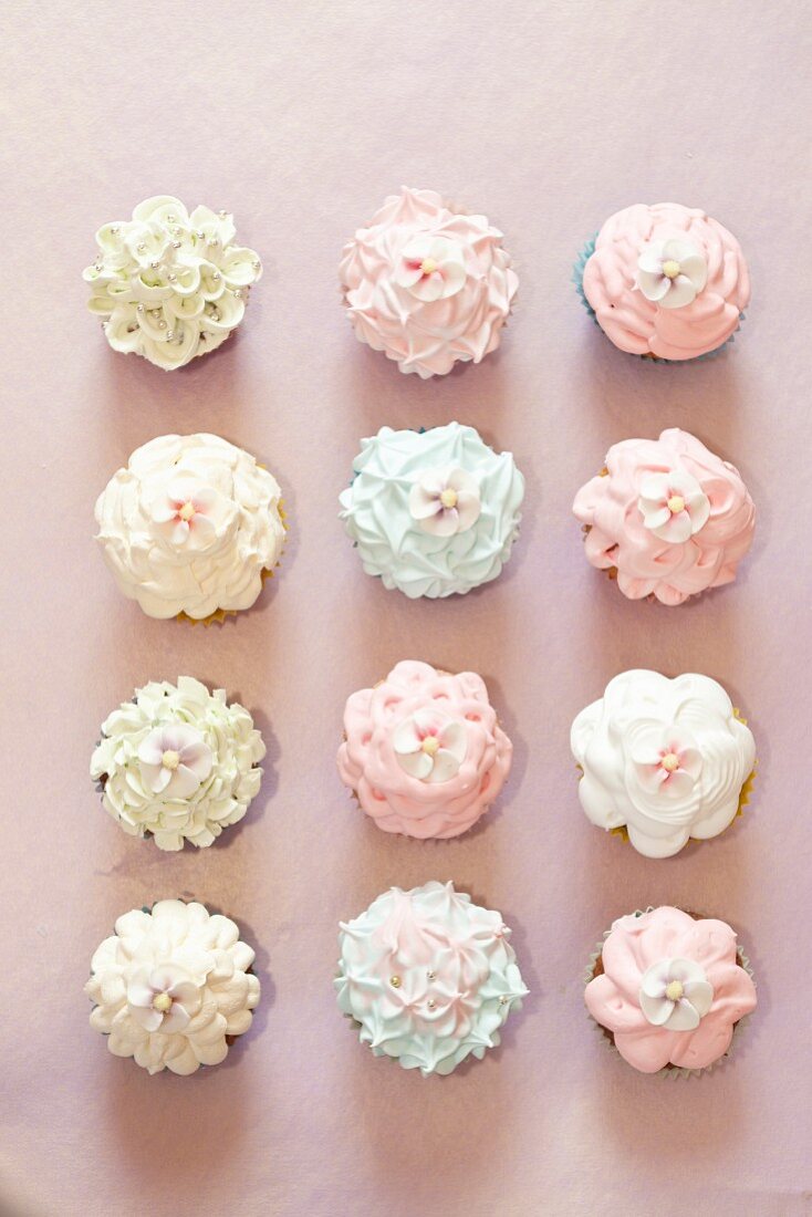 Various cupcakes topped with frosting and sugar flowers