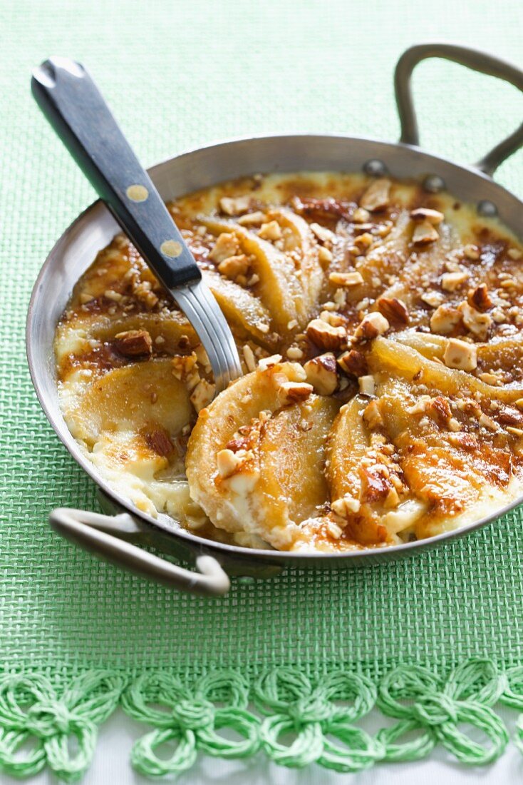 Apple gratin with calvados and hazelnuts in a pan