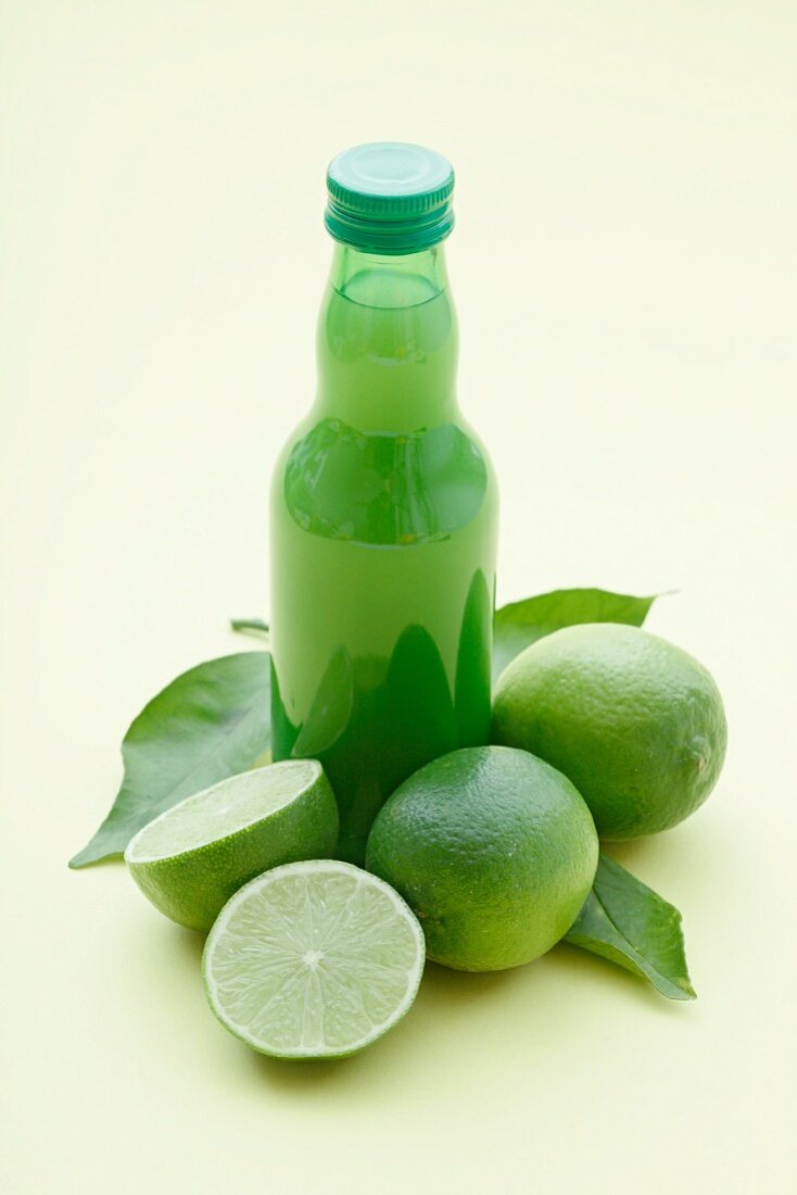 A bottle of lime juice and fresh limes