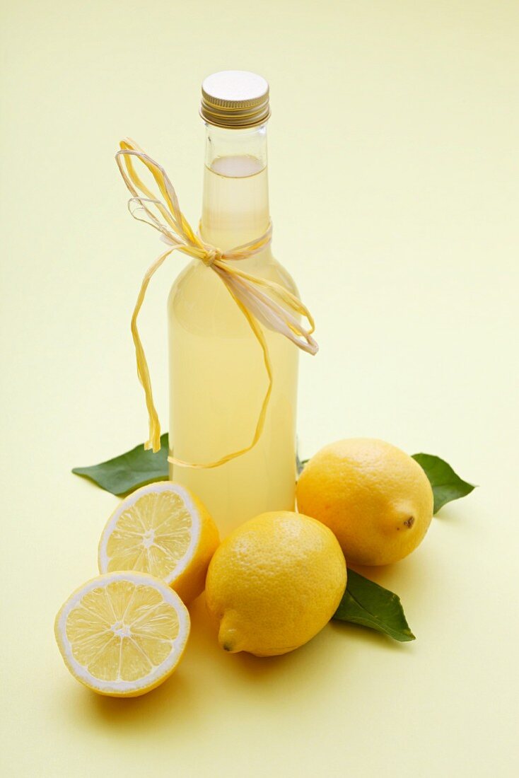 A bottle of lemonade and fresh lemons