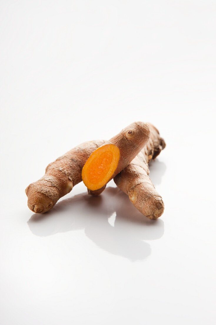 A slice turmeric root on a white surface