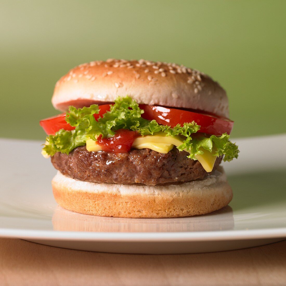 A cheeseburger with tomatoes and a lettuce leaf