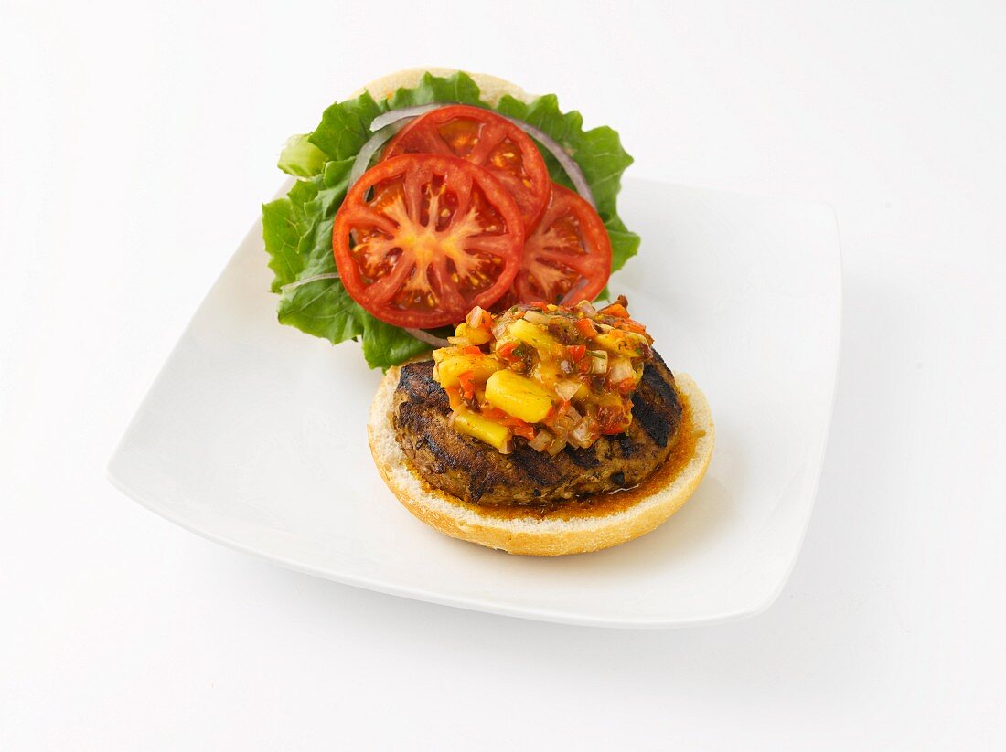 Open Grilled Turkey Burger with Mango Salsa, Tomato and Lettuce; On White Plate on White Background