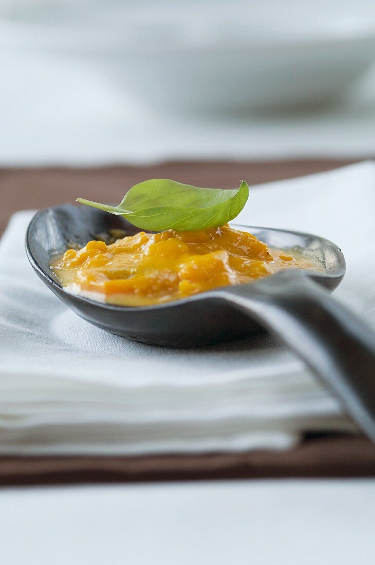 Pumpkin soup with basil on a spoon