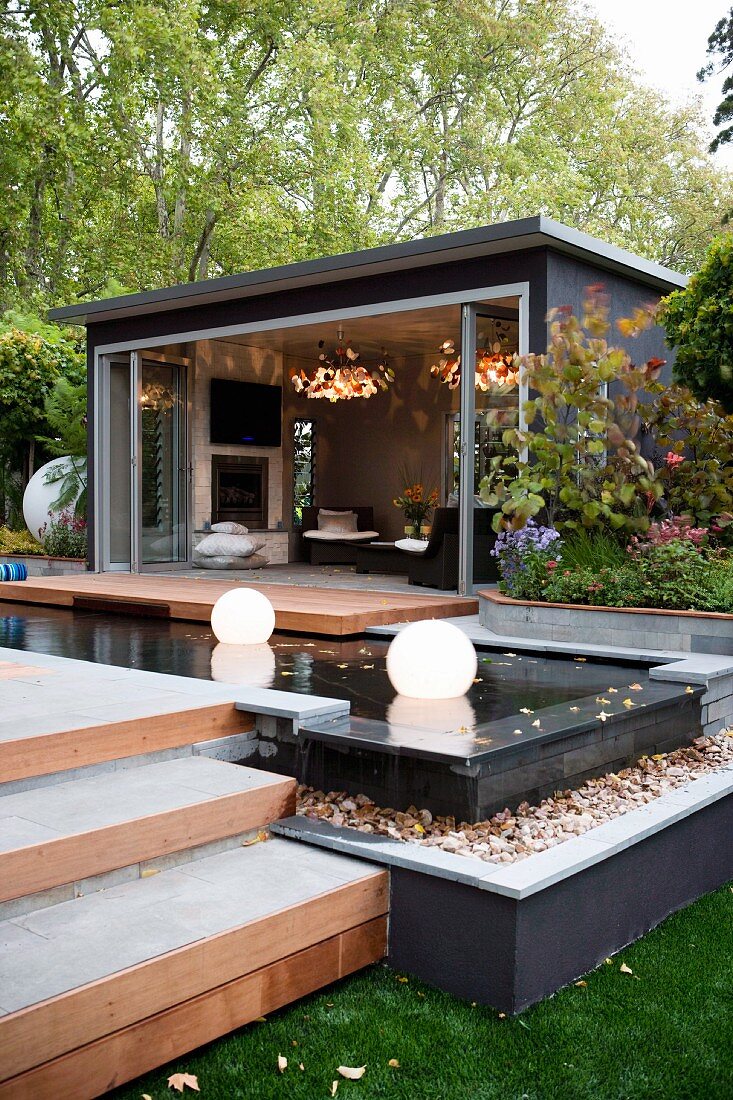 Terrace in front of living room with wooden deck and spherical lamps in pool