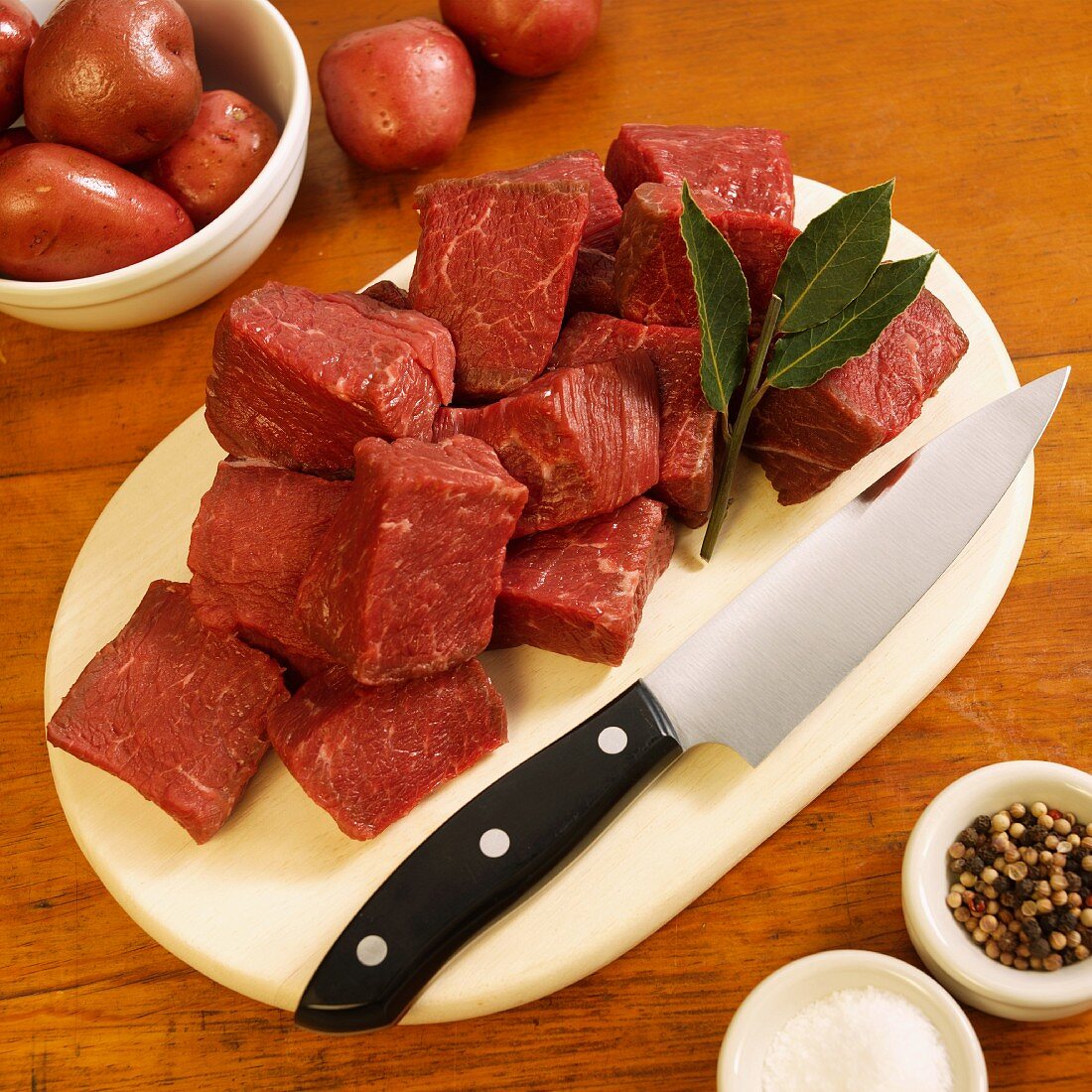 Cubed Grass Fed Beef Sirloin Tips on Cutting Board; Peppercorns, Salt and Red Potatoes